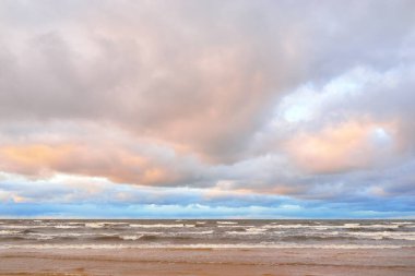 Gün batımında Baltık kıyısı. Kumsal manzarası (kum tepeleri). Dramatik günbatımı gökyüzü, parlayan bulutlar. Idyllic manzara. Doğa, tatiller, eğlence. Çevre turizmi. Panoramik görünüm