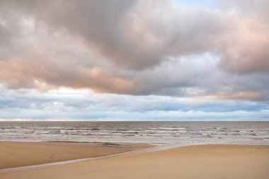 Gün batımında Baltık kıyısı. Kumsal manzarası (kum tepeleri). Dramatik günbatımı gökyüzü, parlayan bulutlar. Idyllic manzara. Doğa, tatiller, eğlence. Çevre turizmi. Panoramik görünüm