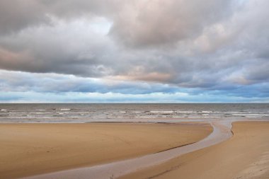 Gün batımında Baltık kıyısı. Kumsal manzarası (kum tepeleri). Dramatik günbatımı gökyüzü, parlayan bulutlar. Idyllic manzara. Doğa, tatiller, eğlence. Çevre turizmi. Panoramik görünüm