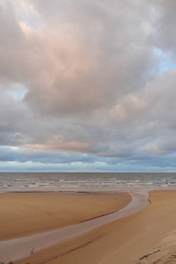Gün batımında Baltık kıyısı. Kumsal manzarası (kum tepeleri). Dramatik günbatımı gökyüzü, parlayan bulutlar. Idyllic manzara. Doğa, tatiller, eğlence. Çevre turizmi. Panoramik görünüm