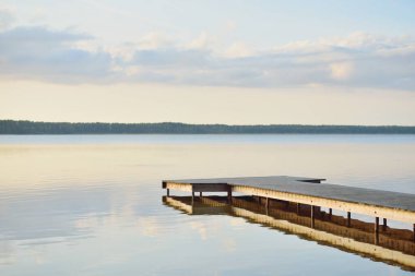 Orman Gölü (nehir) gün batımında. Ahşap iskele. Parlayan bulutlar, durgun ve berrak suda simetri yansımaları. Idyllic manzara. Doğa, ekoloji, ekolojik rezerv, eko-turizm, yürüyüş, tatiller