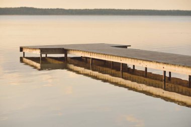 Orman Gölü (nehir) gün batımında. Ahşap iskele. Parlayan bulutlar, durgun ve berrak suda simetri yansımaları. Idyllic manzara. Doğa, ekoloji, ekolojik rezerv, eko-turizm, yürüyüş, tatiller