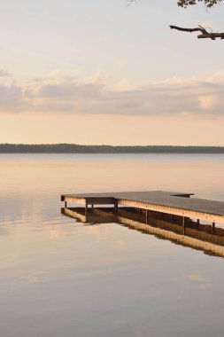 Orman Gölü (nehir) gün batımında. Ahşap iskele. Parlayan bulutlar, durgun ve berrak suda simetri yansımaları. Idyllic manzara. Doğa, ekoloji, ekolojik rezerv, eko-turizm, yürüyüş, tatiller