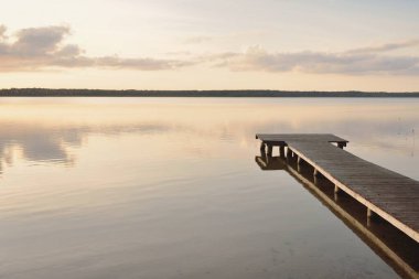 Orman Gölü (nehir) gün batımında. Ahşap iskele. Parlayan bulutlar, durgun ve berrak suda simetri yansımaları. Idyllic manzara. Doğa, ekoloji, ekolojik rezerv, eko-turizm, yürüyüş, tatiller