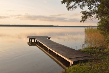 Orman Gölü (nehir) gün batımında. Ahşap iskele. Parlayan bulutlar, durgun ve berrak suda simetri yansımaları. Idyllic manzara. Doğa, ekoloji, ekolojik rezerv, eko-turizm, yürüyüş, tatiller