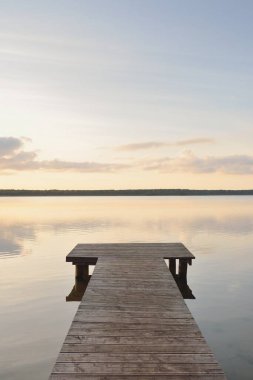 Orman Gölü (nehir) gün batımında. Ahşap iskele. Parlayan bulutlar, durgun ve berrak suda simetri yansımaları. Idyllic manzara. Doğa, ekoloji, ekolojik rezerv, eko-turizm, yürüyüş, tatiller
