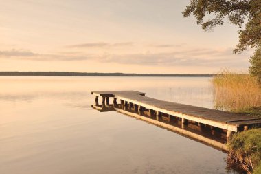 Orman Gölü (nehir) gün batımında. Ahşap iskele. Parlayan bulutlar, durgun ve berrak suda simetri yansımaları. Idyllic manzara. Doğa, ekoloji, ekolojik rezerv, eko-turizm, yürüyüş, tatiller