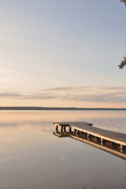 Orman Gölü (nehir) gün batımında. Ahşap iskele. Parlayan bulutlar, durgun ve berrak suda simetri yansımaları. Idyllic manzara. Doğa, ekoloji, ekolojik rezerv, eko-turizm, yürüyüş, tatiller