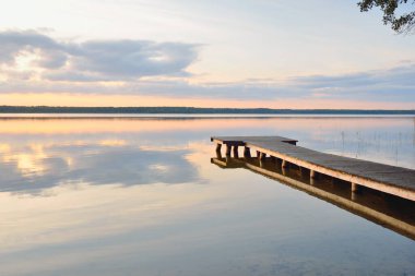 Orman Gölü (nehir) gün batımında. Ahşap iskele. Parlayan bulutlar, durgun ve berrak suda simetri yansımaları. Idyllic manzara. Doğa, ekoloji, ekolojik rezerv, eko-turizm, yürüyüş, tatiller