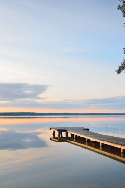 Orman Gölü (nehir) gün batımında. Ahşap iskele. Parlayan bulutlar, durgun ve berrak suda simetri yansımaları. Idyllic manzara. Doğa, ekoloji, ekolojik rezerv, eko-turizm, yürüyüş, tatiller