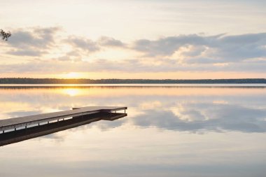 Orman Gölü (nehir) gün batımında. Ahşap iskele. Parlayan bulutlar, durgun ve berrak suda simetri yansımaları. Idyllic manzara. Doğa, ekoloji, ekolojik rezerv, eko-turizm, yürüyüş, tatiller