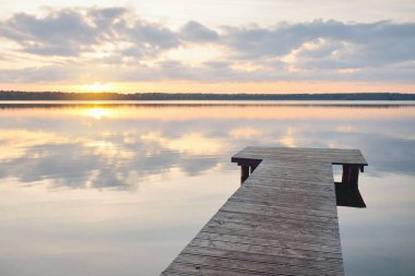 Orman Gölü (nehir) gün batımında. Ahşap iskele. Parlayan bulutlar, durgun ve berrak suda simetri yansımaları. Idyllic manzara. Doğa, ekoloji, ekolojik rezerv, eko-turizm, yürüyüş, tatiller