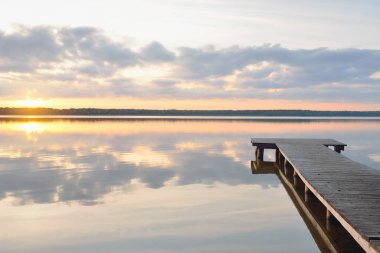 Orman Gölü (nehir) gün batımında. Ahşap iskele. Parlayan bulutlar, durgun ve berrak suda simetri yansımaları. Idyllic manzara. Doğa, ekoloji, ekolojik rezerv, eko-turizm, yürüyüş, tatiller