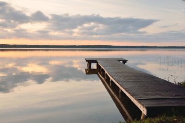 Orman Gölü (nehir) gün batımında. Ahşap iskele. Parlayan bulutlar, durgun ve berrak suda simetri yansımaları. Idyllic manzara. Doğa, ekoloji, ekolojik rezerv, eko-turizm, yürüyüş, tatiller