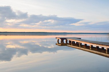 Orman Gölü (nehir) gün batımında. Ahşap iskele. Parlayan bulutlar, durgun ve berrak suda simetri yansımaları. Idyllic manzara. Doğa, ekoloji, ekolojik rezerv, eko-turizm, yürüyüş, tatiller