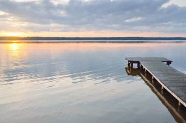 Orman Gölü (nehir) gün batımında. Ahşap iskele. Parlayan bulutlar, durgun ve berrak suda simetri yansımaları. Idyllic manzara. Doğa, ekoloji, ekolojik rezerv, eko-turizm, yürüyüş, tatiller