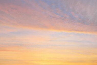 Parlayan pembe, altın rengi sirrus ve kümülüs bulutlarıyla açık mavi gökyüzü. Gün doğumu. Dramatik bulut manzarası. Sanat, meteoroloji, cennet, umut, barış, grafik kaynakları, resimli panoramik manzara