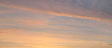 Parlayan pembe, altın rengi sirrus ve kümülüs bulutlarıyla açık mavi gökyüzü. Gün doğumu. Dramatik bulut manzarası. Sanat, meteoroloji, cennet, umut, barış, grafik kaynakları, resimli panoramik manzara