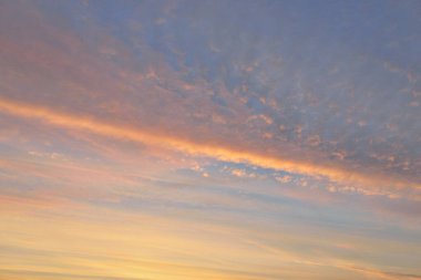 Parlayan pembe, altın rengi sirrus ve kümülüs bulutlarıyla açık mavi gökyüzü. Gün doğumu. Dramatik bulut manzarası. Sanat, meteoroloji, cennet, umut, barış, grafik kaynakları, resimli panoramik manzara