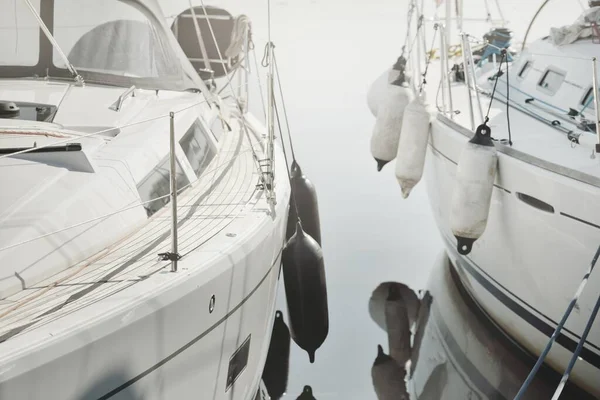 Beyaz modern yelkenli (kiralık ve satılık) yat limanındaki bir rıhtıma demirlemiş. Tahta meşe güvertesi. Denizcilik, ulaşım, amatör yelkencilik, tatiller, gezinti, eğlence kavramları