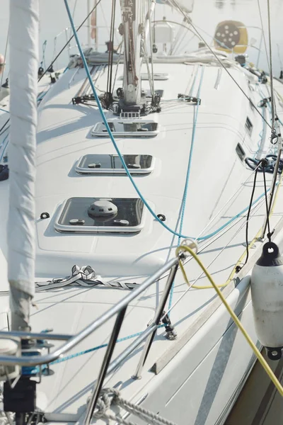 Beyaz modern yelkenli (kiralık ve satılık) yat limanındaki bir rıhtıma demirlemiş. Deniz aracı, ulaşım, amatör yelkencilik, spor, boş zaman aktivitesi, tatiller, gezinti, eğlence kavramları.