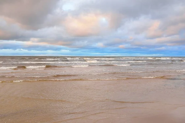 Gün batımında Baltık kıyısı. Kumsal manzarası (kum tepeleri). Dramatik günbatımı gökyüzü, parlayan bulutlar. Idyllic manzara. Doğa, tatiller, eğlence. Çevre turizmi. Panoramik görünüm