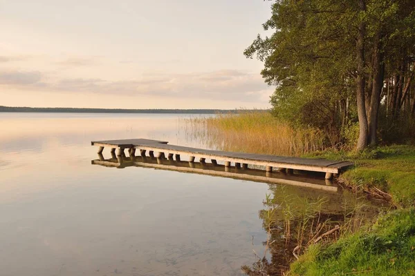 Orman Gölü (nehir) gün batımında. Ahşap iskele. Parlayan bulutlar, durgun ve berrak suda simetri yansımaları. Idyllic manzara. Doğa, ekoloji, ekolojik rezerv, eko-turizm, yürüyüş, tatiller