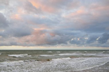 Gün batımında Baltık kıyılarından panoramik manzara. Dramatik bulutlar, parlayan bulutlar, fırtınadan sonra altın güneş ışığı. Doğa, çevre, iklim değişikliği, kararsız hava