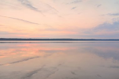 Gün batımında Orman Gölü. Yumuşak güneş ışığı, parlayan bulutlar kristal berrak suda simetri yansımaları. Idyllic manzara. Panoramik manzara. Doğa, ekoloji, çevrecilik. Barış ve neşe kavramları