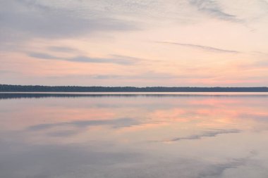 Gün batımında Orman Gölü. Yumuşak güneş ışığı, parlayan bulutlar kristal berrak suda simetri yansımaları. Idyllic manzara. Panoramik manzara. Doğa, ekoloji, çevrecilik. Barış ve neşe kavramları