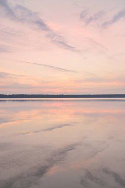 Gün batımında Orman Gölü. Yumuşak güneş ışığı, parlayan bulutlar kristal berrak suda simetri yansımaları. Idyllic manzara. Panoramik manzara. Doğa, ekoloji, çevrecilik. Barış ve neşe kavramları