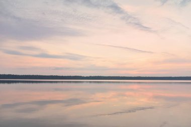 Gün batımında Orman Gölü. Yumuşak güneş ışığı, parlayan bulutlar kristal berrak suda simetri yansımaları. Idyllic manzara. Panoramik manzara. Doğa, ekoloji, çevrecilik. Barış ve neşe kavramları