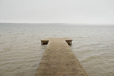 Yoğun bir siste orman nehri (göl). Ahşap iskele. Kasvetli gökyüzü, yağmur. Bulutlu bir gün. Idyllic manzara, kırsal manzara. Doğa, ekoloji, eko-turizm, yürüyüş, ekoloji beldesi, yerel turizm