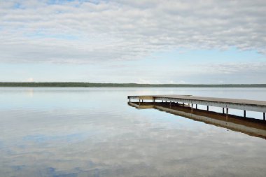 Orman nehri (göl) güneşli bir günde. Ahşap iskele. Clea gökyüzü, kristal berrak suda yansıyor. Idyllic manzara, kırsal manzara. Doğa, ekoloji, eko-turizm, yürüyüş, ekoloji beldesi, yerel turizm