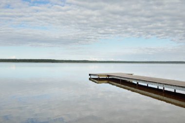 Orman nehri (göl) güneşli bir günde. Ahşap iskele. Clea gökyüzü, kristal berrak suda yansıyor. Idyllic manzara, kırsal manzara. Doğa, ekoloji, eko-turizm, yürüyüş, ekoloji beldesi, yerel turizm