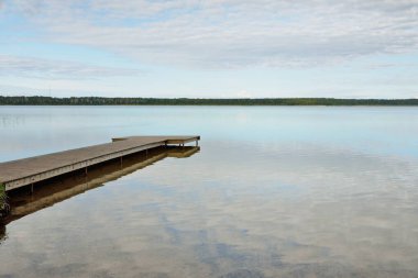 Orman nehri (göl) güneşli bir günde. Ahşap iskele. Clea gökyüzü, kristal berrak suda yansıyor. Idyllic manzara, kırsal manzara. Doğa, ekoloji, eko-turizm, yürüyüş, ekoloji beldesi, yerel turizm