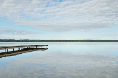 Orman nehri (göl) güneşli bir günde. Ahşap iskele. Clea gökyüzü, kristal berrak suda yansıyor. Idyllic manzara, kırsal manzara. Doğa, ekoloji, eko-turizm, yürüyüş, ekoloji beldesi, yerel turizm