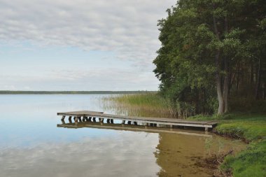 Orman nehri (göl) güneşli bir günde. Ahşap iskele. Clea gökyüzü, kristal berrak suda yansıyor. Idyllic manzara, kırsal manzara. Doğa, ekoloji, eko-turizm, yürüyüş, ekoloji beldesi, yerel turizm