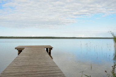 Orman nehri (göl) güneşli bir günde. Ahşap iskele. Clea gökyüzü, kristal berrak suda yansıyor. Idyllic manzara, kırsal manzara. Doğa, ekoloji, eko-turizm, yürüyüş, ekoloji beldesi, yerel turizm