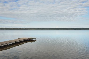Orman nehri (göl) güneşli bir günde. Ahşap iskele. Clea gökyüzü, kristal berrak suda yansıyor. Idyllic manzara, kırsal manzara. Doğa, ekoloji, eko-turizm, yürüyüş, ekoloji beldesi, yerel turizm
