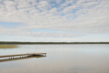 Orman nehri (göl) güneşli bir günde. Ahşap iskele. Clea gökyüzü, kristal berrak suda yansıyor. Idyllic manzara, kırsal manzara. Doğa, ekoloji, eko-turizm, yürüyüş, ekoloji beldesi, yerel turizm