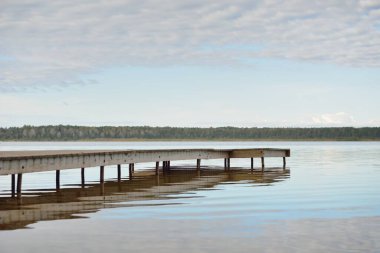 Orman nehri (göl) güneşli bir günde. Ahşap iskele. Clea gökyüzü, kristal berrak suda yansıyor. Idyllic manzara, kırsal manzara. Doğa, ekoloji, eko-turizm, yürüyüş, ekoloji beldesi, yerel turizm