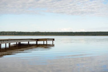 Orman nehri (göl) güneşli bir günde. Ahşap iskele. Clea gökyüzü, kristal berrak suda yansıyor. Idyllic manzara, kırsal manzara. Doğa, ekoloji, eko-turizm, yürüyüş, ekoloji beldesi, yerel turizm