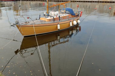 Modern klasik ahşap İsveçli yelkenli teknesi yat limanındaki bir iskeleye demirlemiş. Turizm, tatiller, boş zaman aktiviteleri, eğlence, yelkencilik temaları
