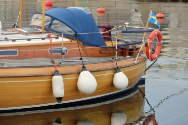 Modern klasik ahşap İsveçli yelkenli teknesi yat limanındaki bir iskeleye demirlemiş. Turizm, tatiller, boş zaman aktiviteleri, eğlence, yelkencilik temaları