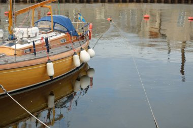 Modern klasik ahşap İsveçli yelkenli teknesi yat limanındaki bir iskeleye demirlemiş. Turizm, tatiller, boş zaman aktiviteleri, eğlence, yelkencilik temaları
