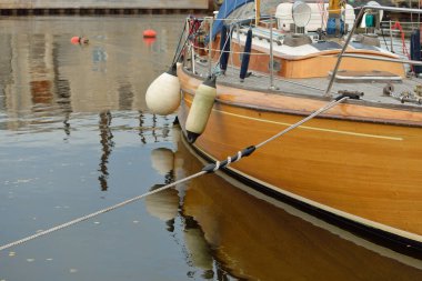 Modern klasik ahşap İsveçli yelkenli teknesi yat limanındaki bir iskeleye demirlemiş. Turizm, tatiller, boş zaman aktiviteleri, eğlence, yelkencilik temaları