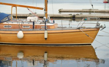 Modern klasik ahşap İsveçli yelkenli teknesi yat limanındaki bir iskeleye demirlemiş. Turizm, tatiller, boş zaman aktiviteleri, eğlence, yelkencilik temaları