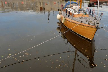 Modern klasik ahşap İsveçli yelkenli teknesi yat limanındaki bir iskeleye demirlemiş. Turizm, tatiller, boş zaman aktiviteleri, eğlence, yelkencilik temaları