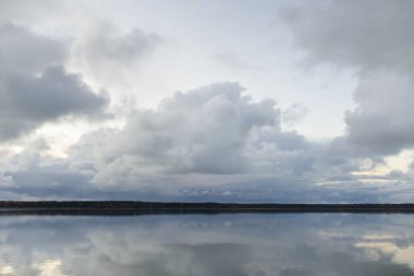 Gün batımında Orman Nehri (Lake). Dramatik gökyüzü, karanlık, parlak bulutlar. Kristal berrak suda simetri yansımaları. Panoramik sonbahar manzarası. Doğa, çevre, ekoloji, hava durumu, iklim değişikliği